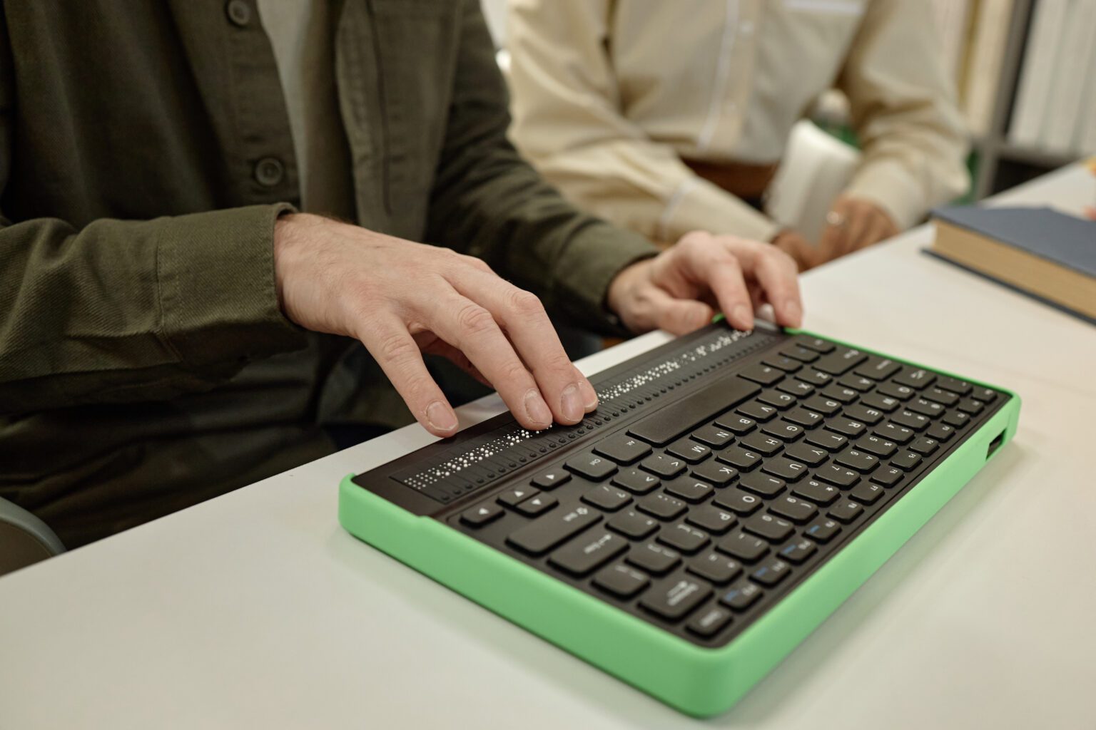 Young Man Using Braille Keyboard While Reading Book in Library